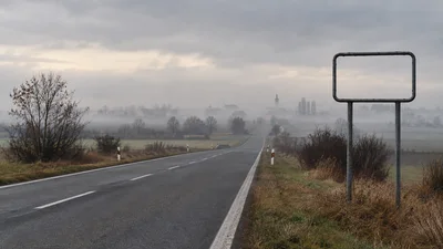 Prázdna cesta na Záhorí smeruje do hmly popri ráme bez obecnej tabule